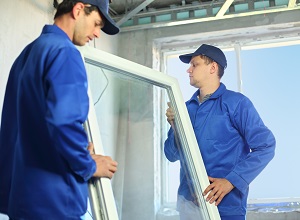 Two workers in blue work clothes set a new window